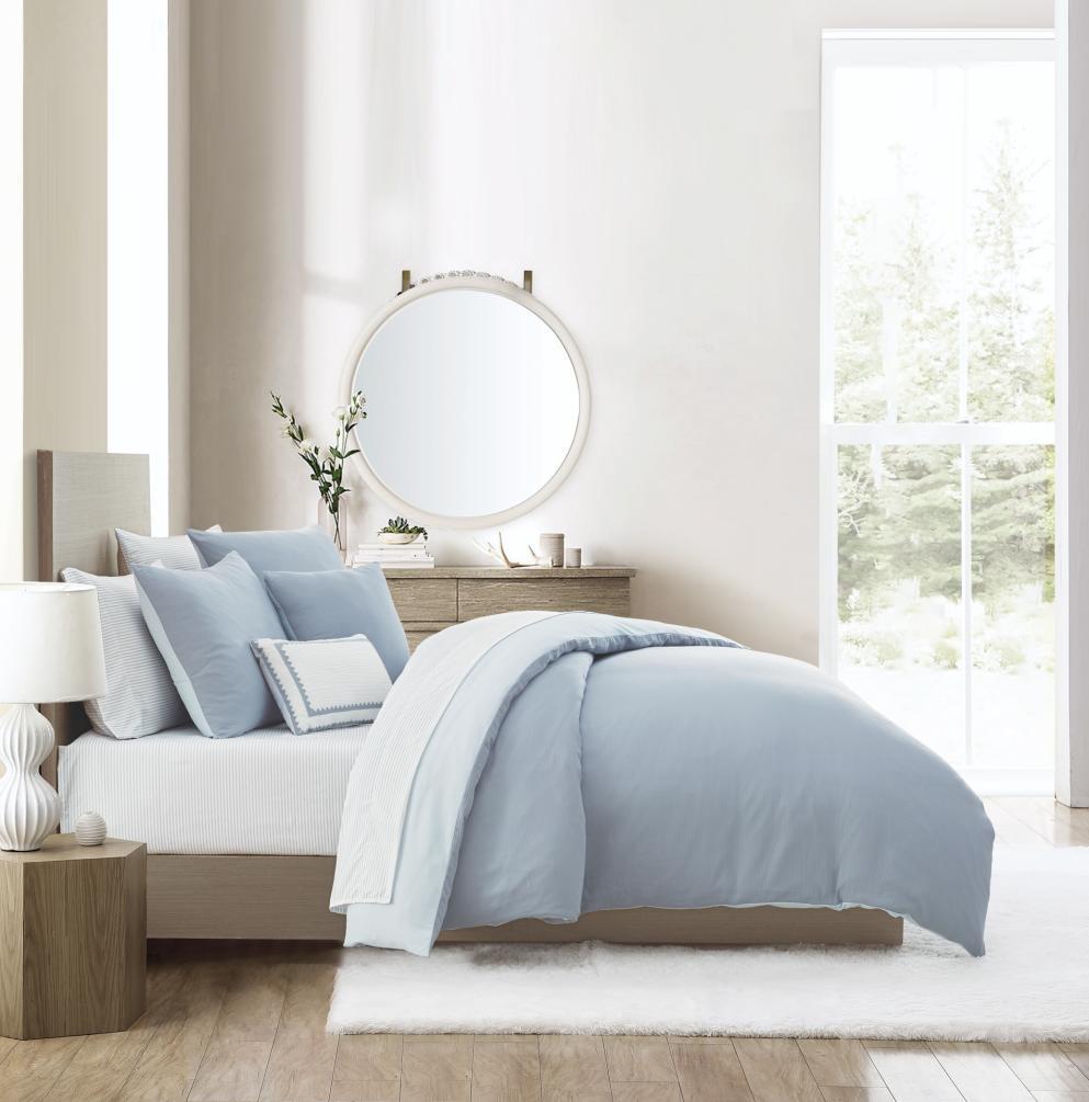 Blue bedding collection photographed in a bright room set with a round mirror
